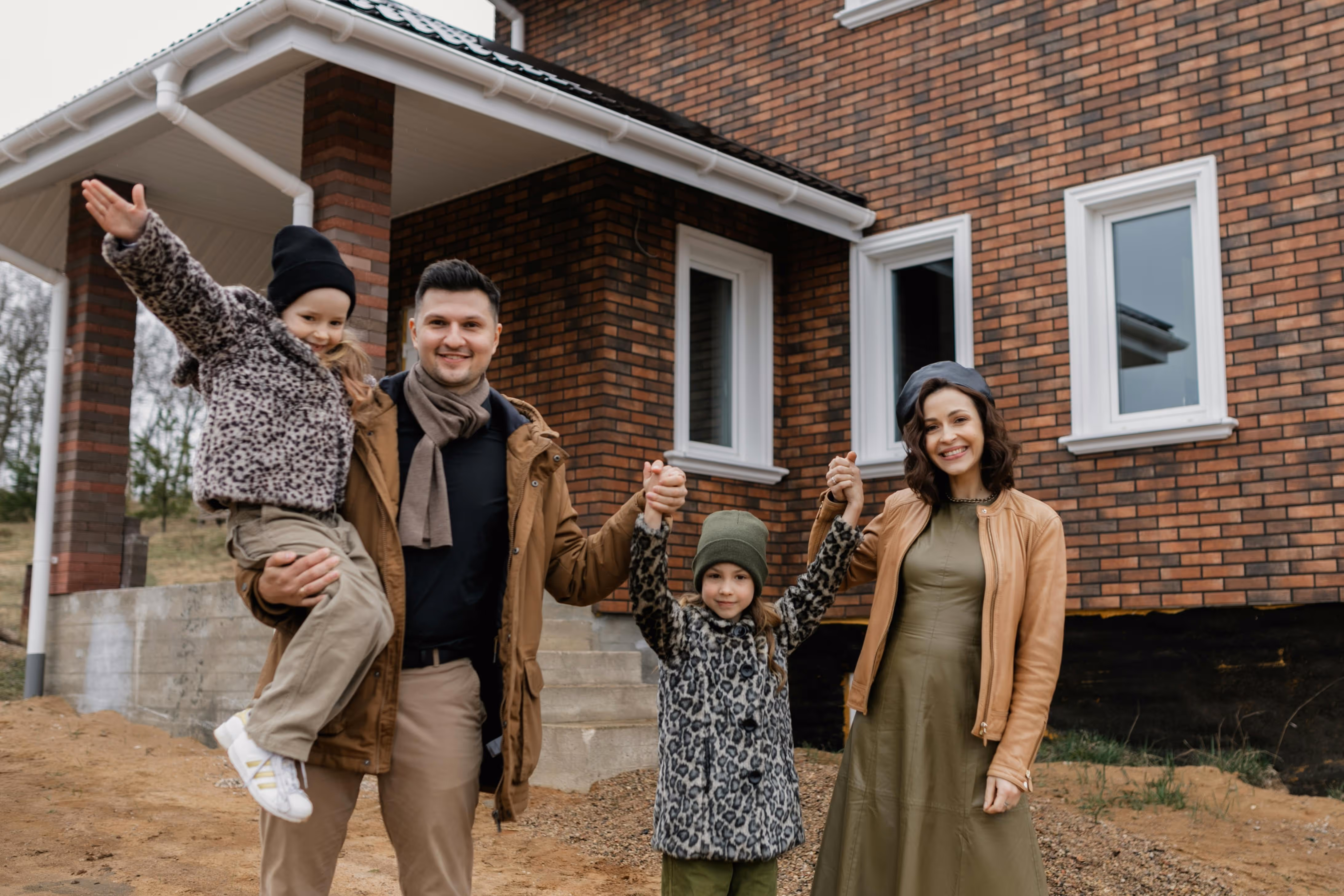 Happy family standing in front of their new home